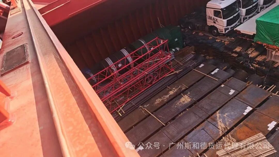 Steel plates and a red steel frame stowed in a break bulk vessel hold for Tema, Ghana